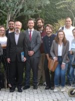 Foto do grupo de alunos e palestrantes num ambiente externo com árvores em volta.