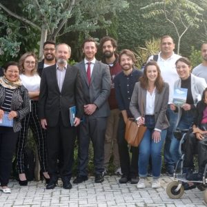 Foto do grupo de alunos e palestrantes num ambiente externo com árvores em volta.